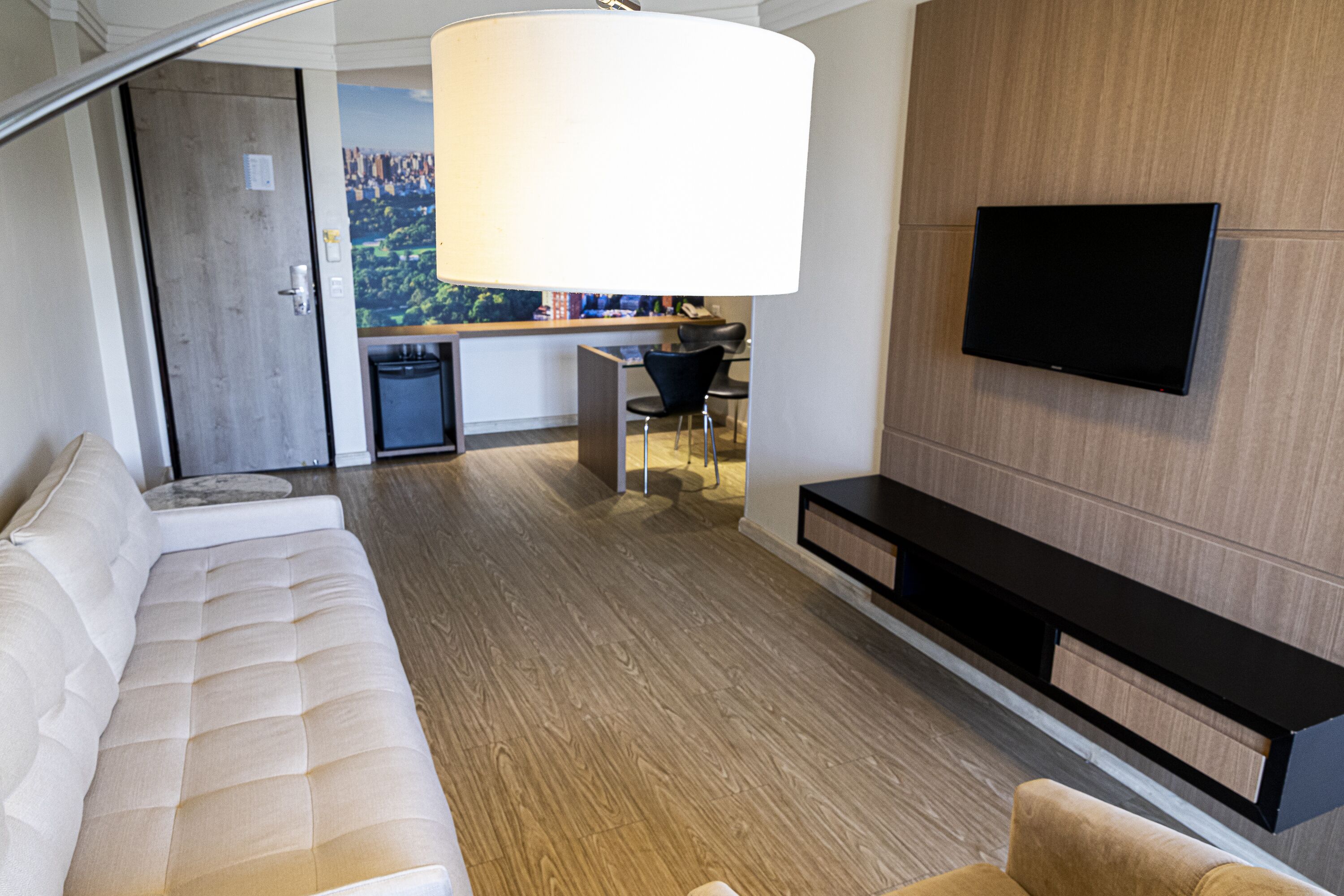 Un soggiorno moderno con un divano, una TV a parete e un'area pranzo sullo sfondo.