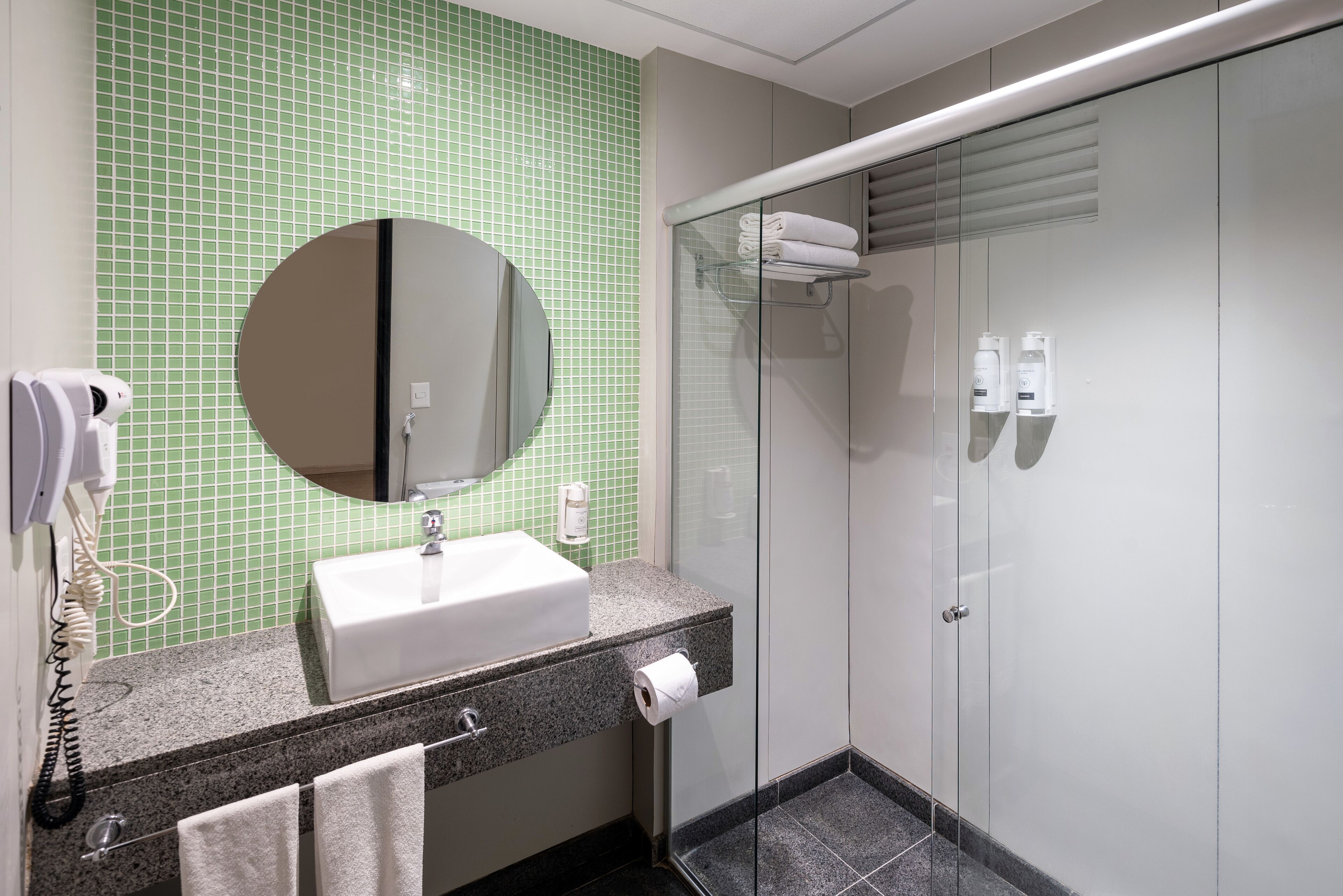 Un baño moderno con lavamanos, espejo y cabina de ducha de vidrio.
