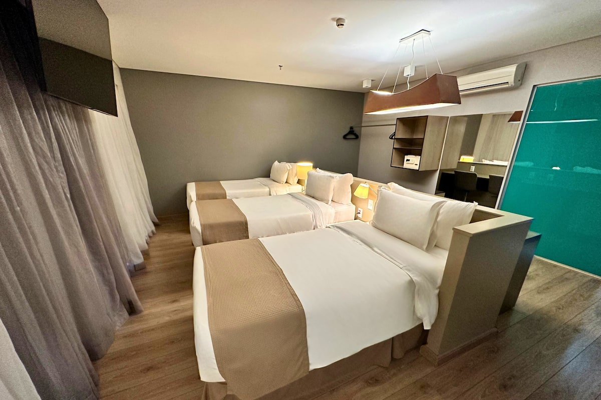 Une chambre d’hôtel avec deux lits, un plancher en bois, un mur vert et une fenêtre.