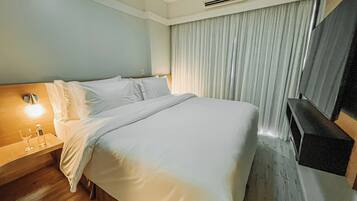 Habitación de hotel con cama, mesita de noche con un vaso de agua y aire acondicionado de pared.