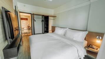 A hotel room with a large bed, a bedside table with a lamp, a wardrobe, and a mirror.