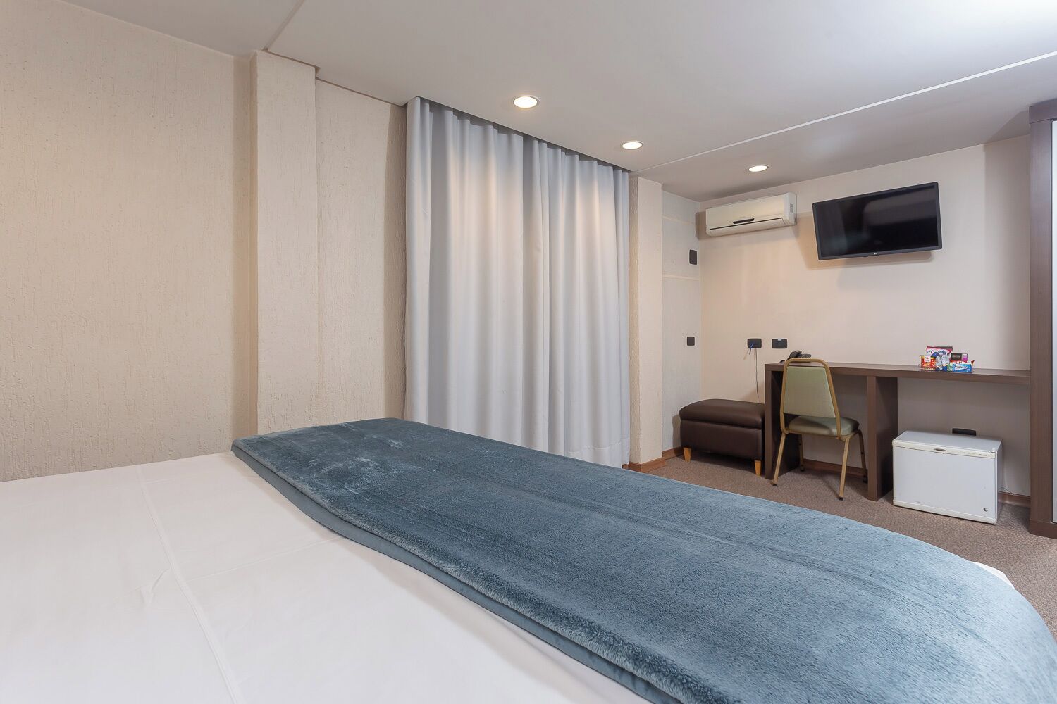 Une chambre d’hôtel équipée d’un lit, d’un bureau, d’une chaise, d’une télévision et d’un appareil de climatisation.