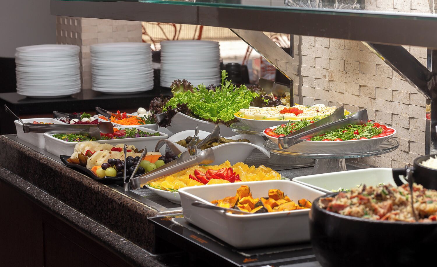 En buffet med et udvalg af retter, herunder salater, frugt og grøntsager.