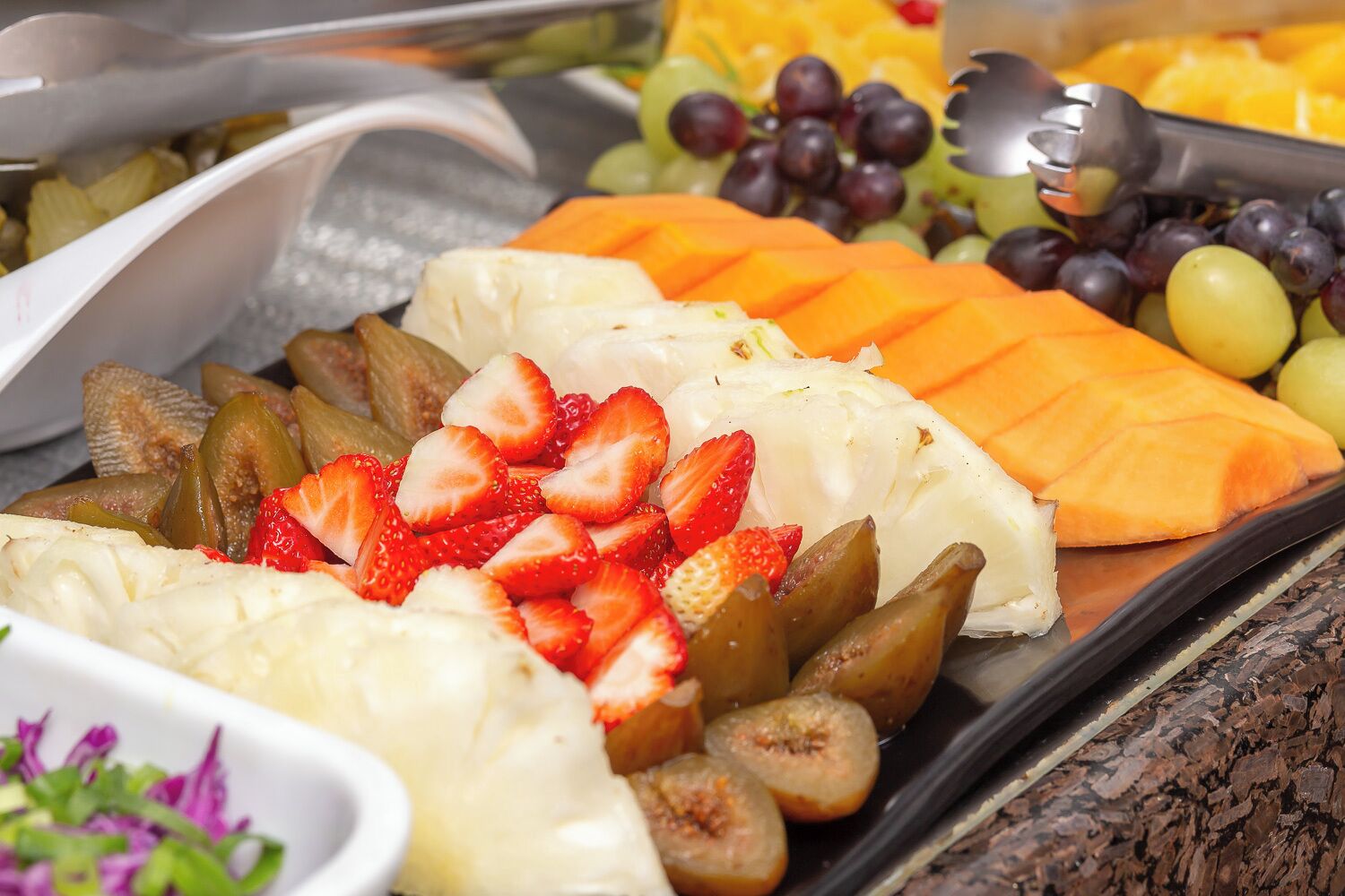 Una bandeja de frutas con fresas, higos y melón.