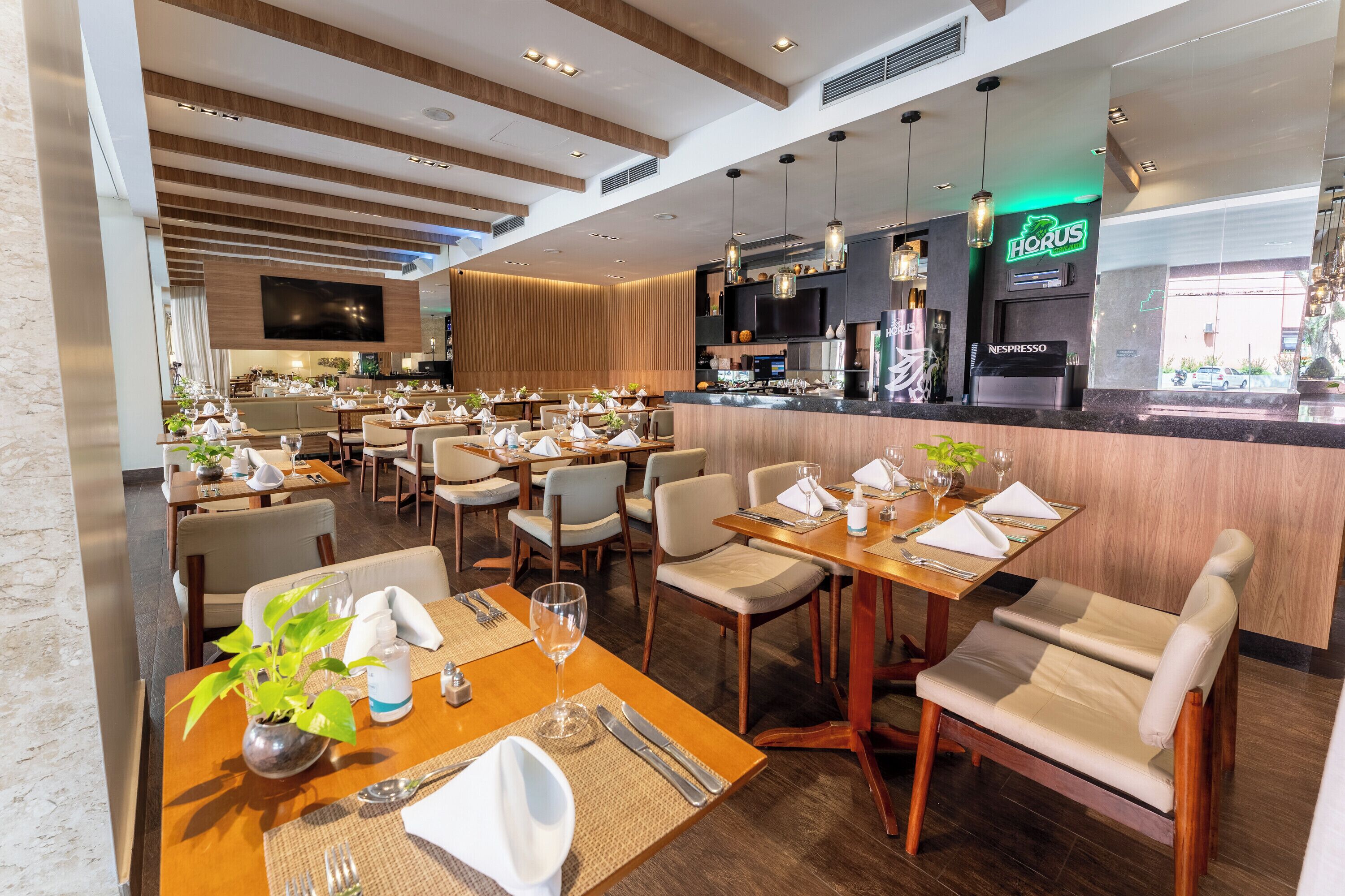 Un restaurante con varias mesas, sillas y una zona de bar.