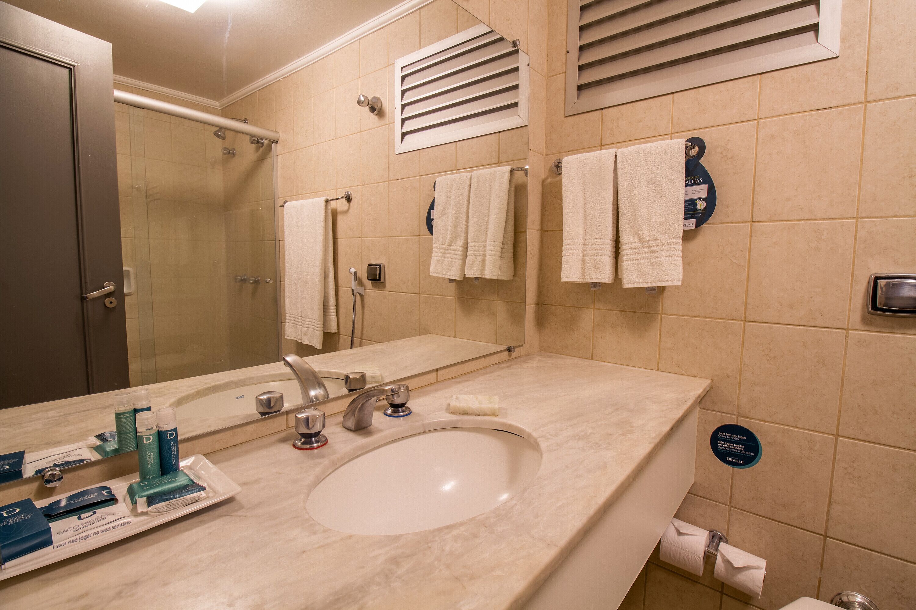 A bathroom with a sink, mirror, towel rack, and toiletries.