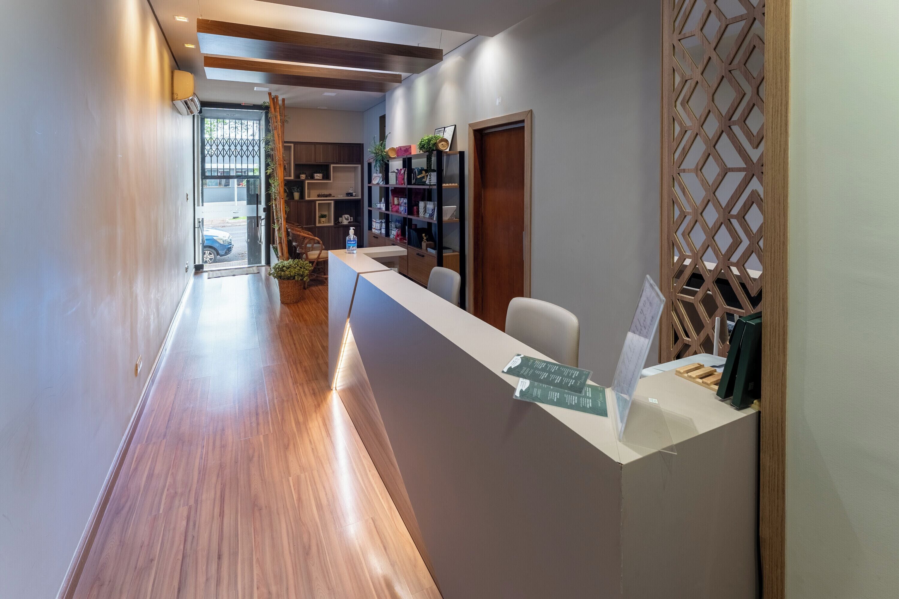 A reception area with a wooden floor, a reception desk, and a wall-mounted display.