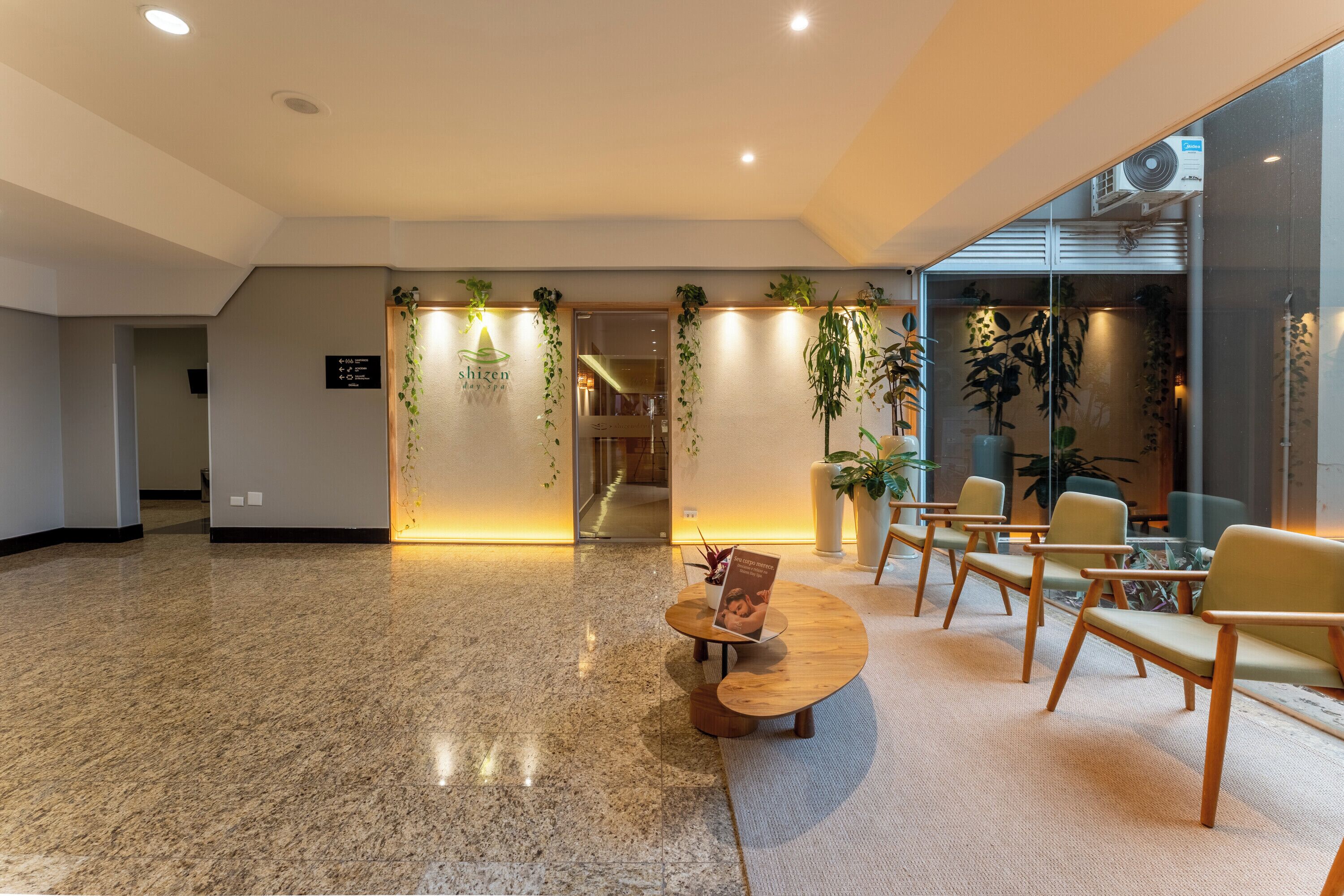 A lobby with a reception desk, seating area, and potted plants.