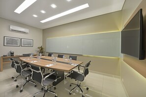 A conference room with a long table, chairs, a whiteboard, and an air conditioning unit. - Deville Prime Maringá (Maringá)