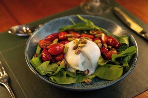 Ensalada con fresas, nueces y una cucharada de crema sobre un plato.