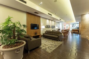 Una sala de estar moderna con televisor de pantalla plana, sofás, una mesa de centro y una planta grande en maceta.