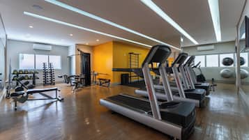 Un gimnasio con cintas de correr, máquinas de pesas y una banca.