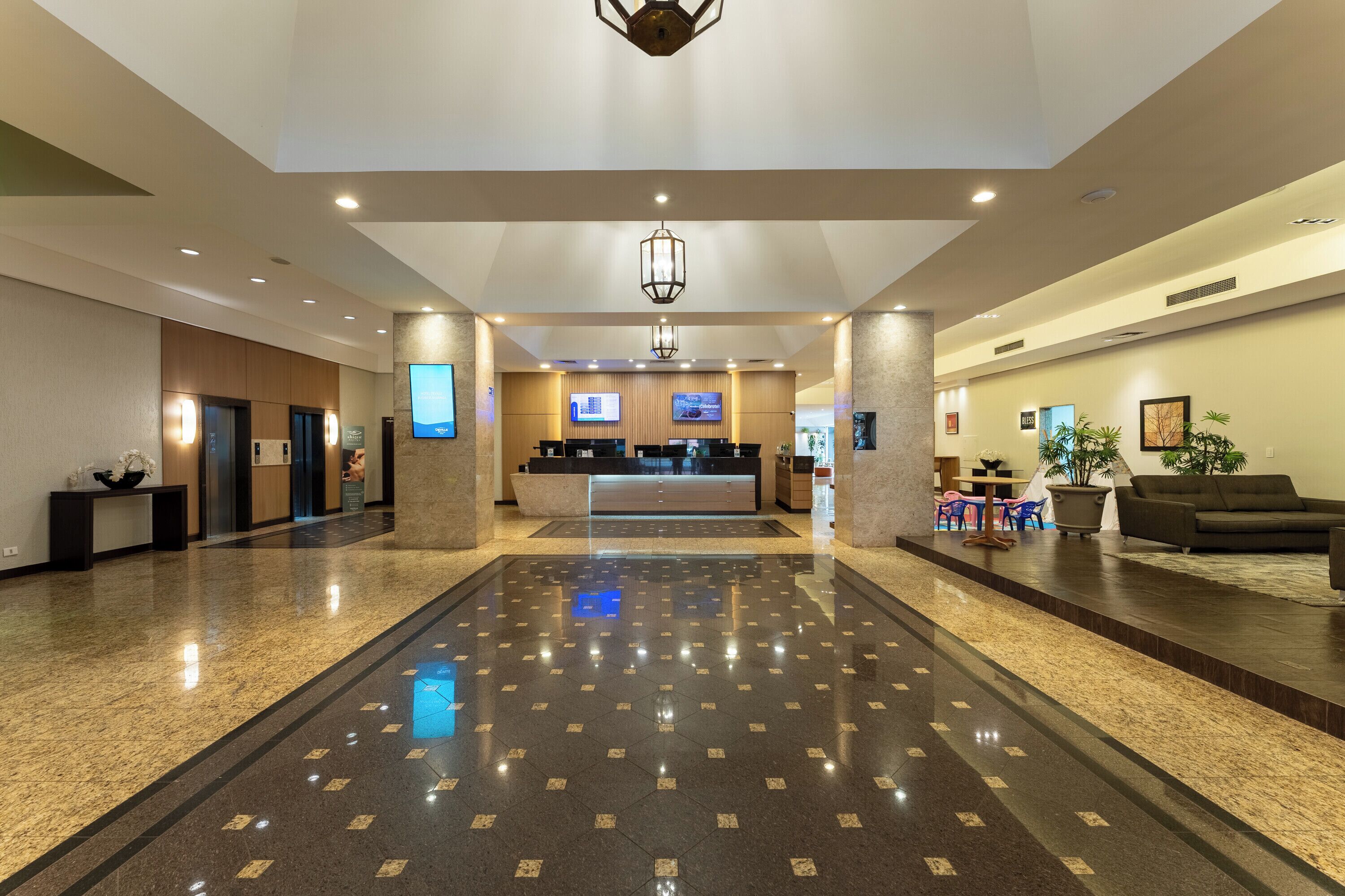 Un vestíbulo de hotel con mostrador de recepción, zona de estar y un espejo grande.