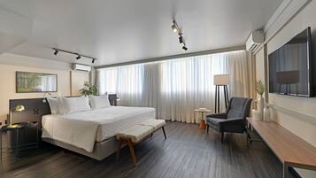 Relax in a serene space with a large bed, desk, and flat-screen TV.