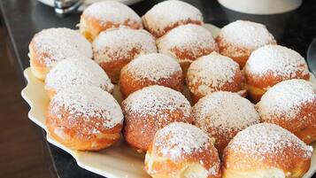 Un bufé con diversos pasteles y postres, incluyendo rosquillas y tartas.