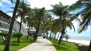 A paved pathway lined with palm trees leading to a beach. - GoldMen Vila do Mar Natal (Natal)