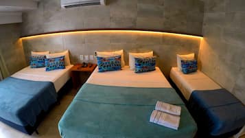 Habitación de hotel con cabecera curvada, dos camas individuales, una cama doble y una mesita de noche con teléfono.