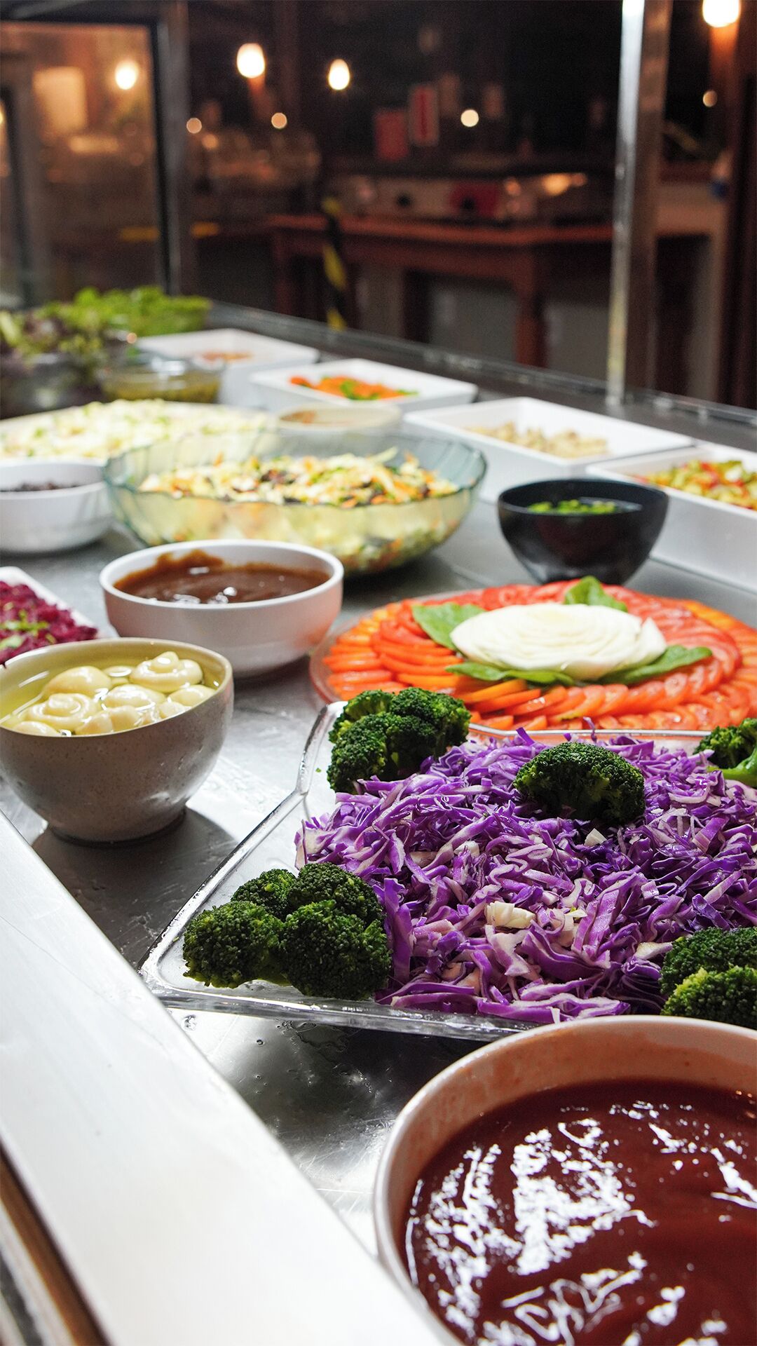 A buffet with various dishes including salads, vegetables, and sauces.