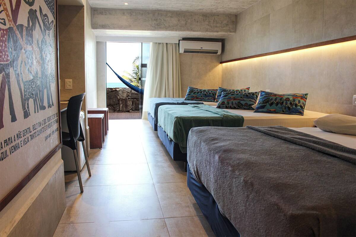 Habitación de hotel con dos camas, un escritorio y una hamaca.