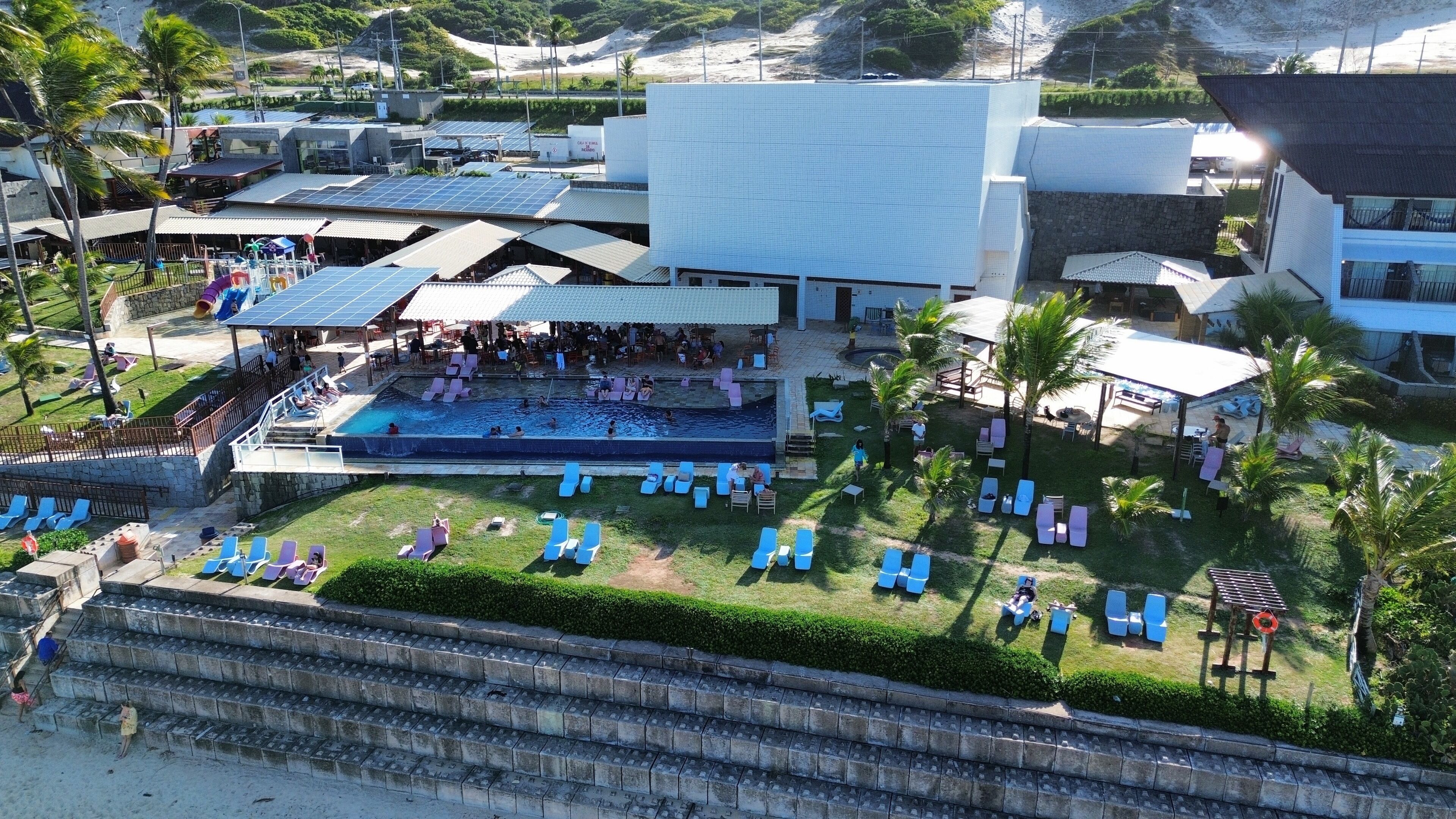 Resort com piscina, espreguiçadeiras e área coberta com palco.