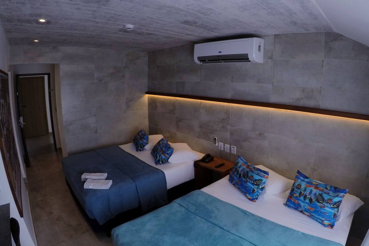 Una habitación de hotel con dos camas, diseño moderno y aire acondicionado.