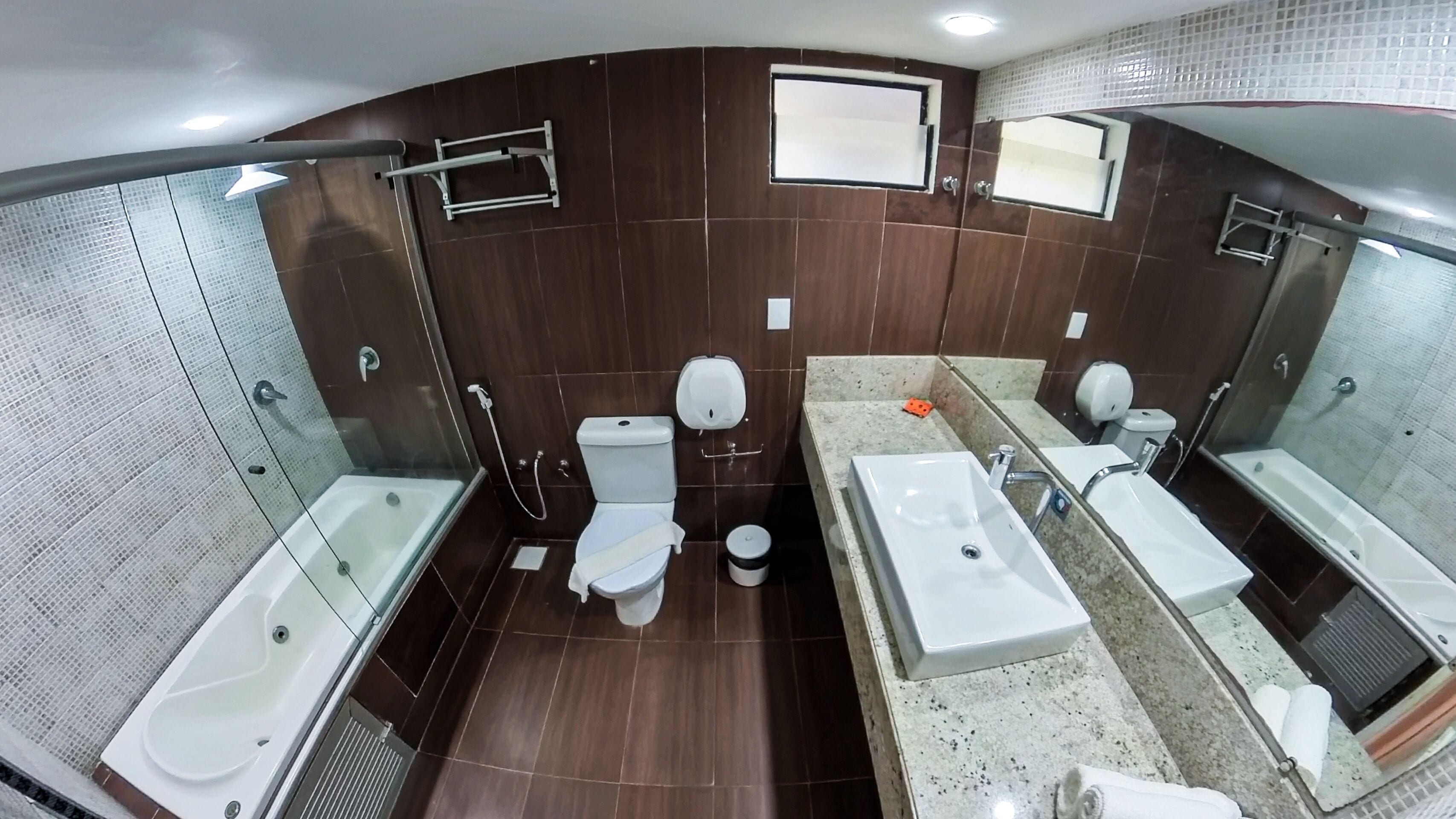 A modern bathroom with a glass shower enclosure, a toilet, a bidet, and a double sink vanity.