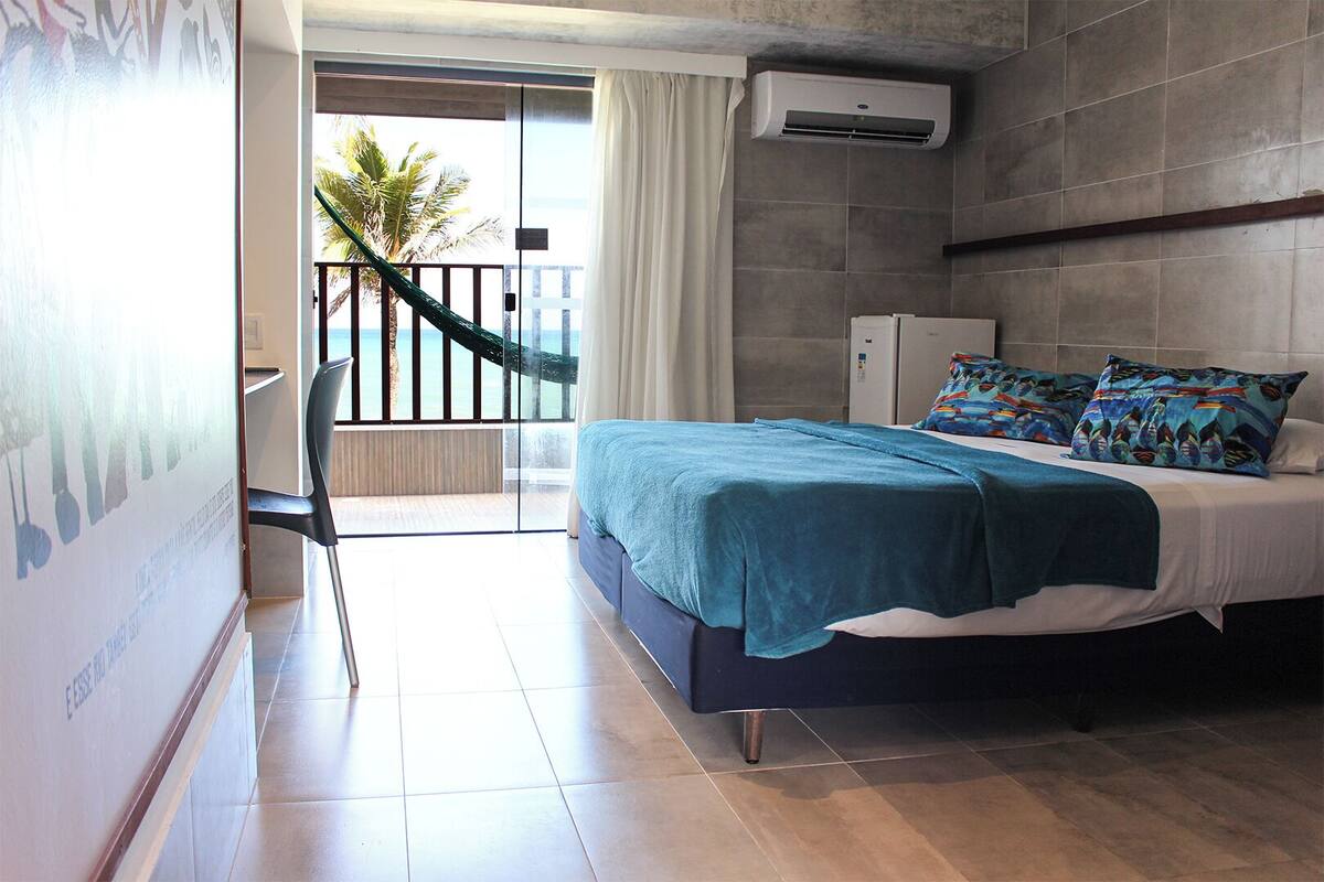 Un dormitorio con cama, balcón y vistas al océano, además de aire acondicionado.