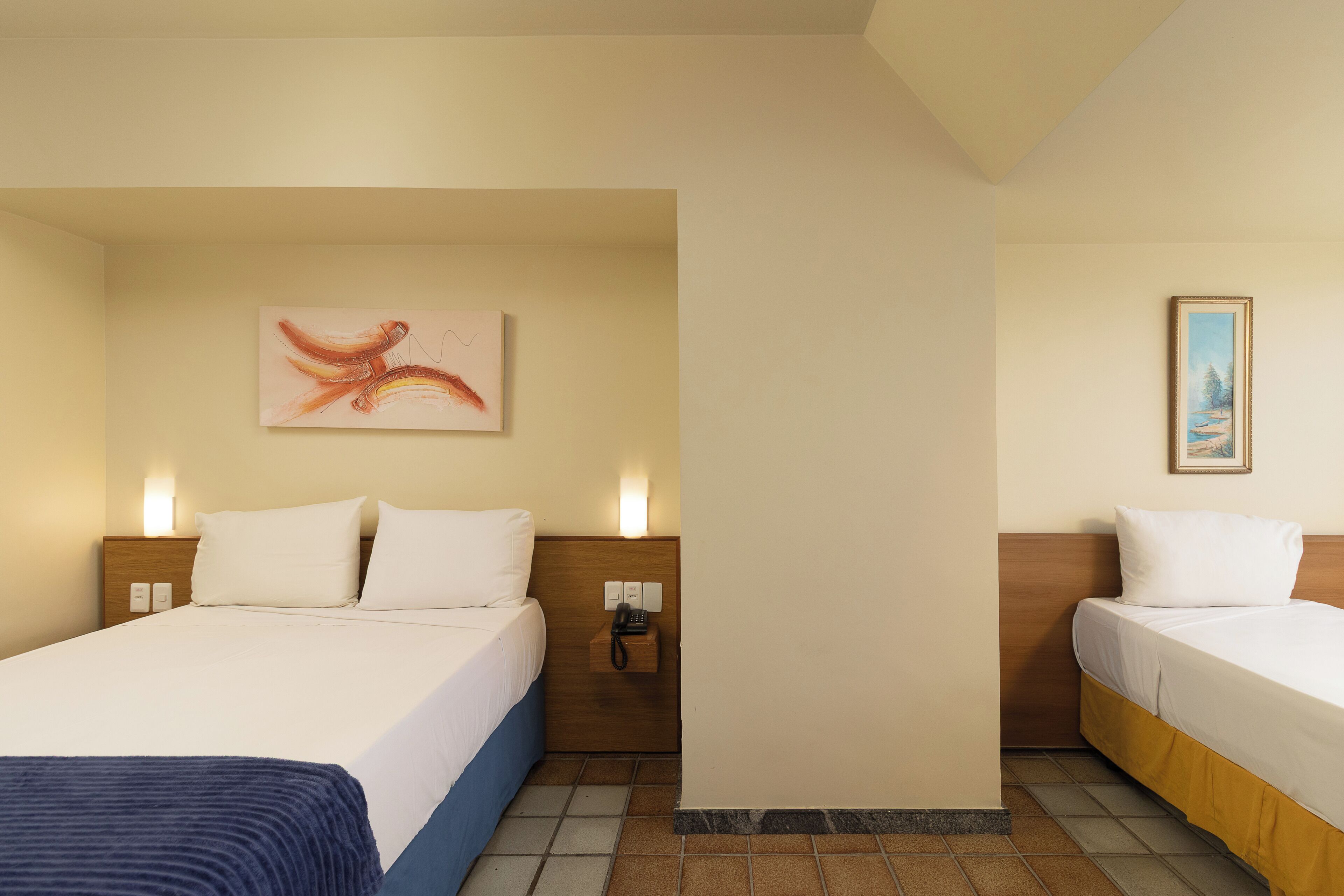 Quarto de hotel com duas camas, um quadro na parede, um telefone e um interruptor de luz.