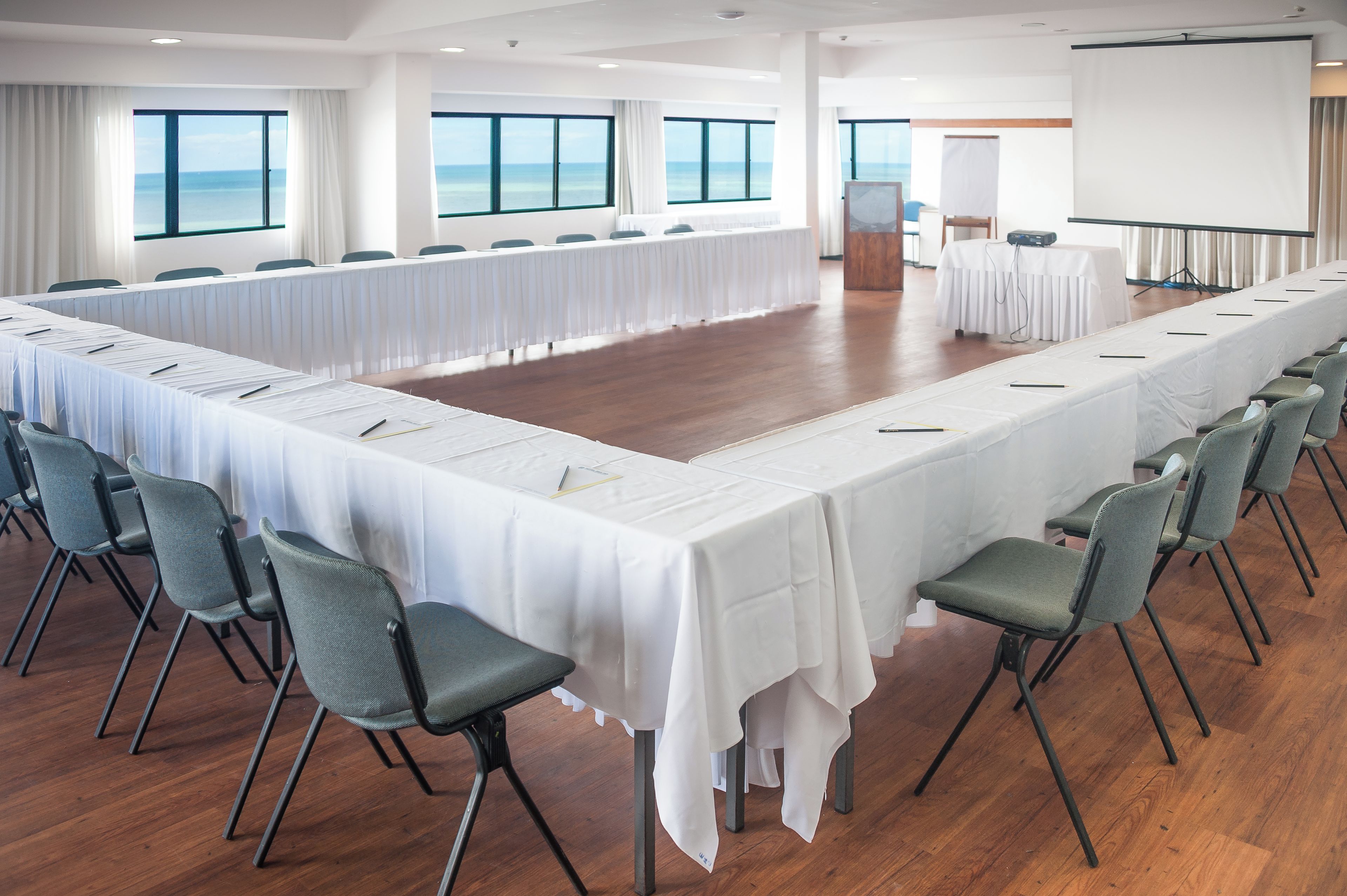 Un salón de conferencias con una larga mesa, sillas y grandes ventanales con vistas.