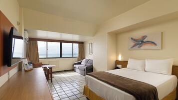 Una habitación de hotel con cama, escritorio, silla, televisor, ventana con vista y un cuadro en la pared.