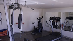 A gym with a treadmill, elliptical, and weight machine.