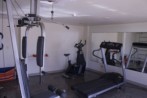 A gym with a treadmill, elliptical, and weight machine.