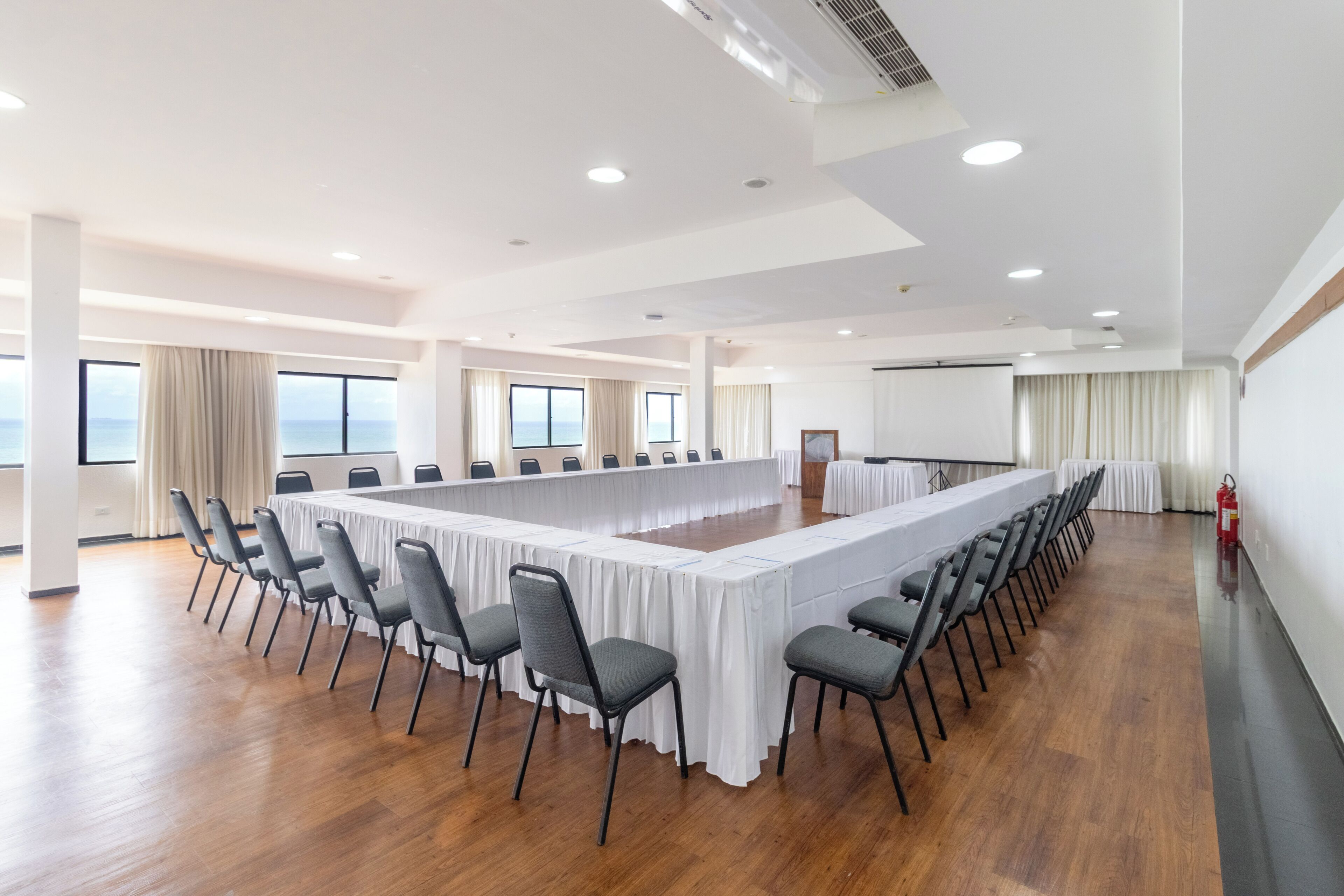 Un salón de conferencias con una larga mesa, sillas y ventanas amplias.