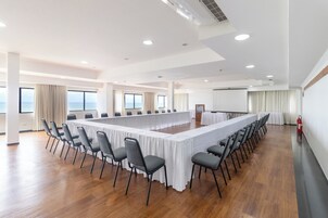 Un salón de conferencias con una larga mesa, sillas y ventanas amplias.