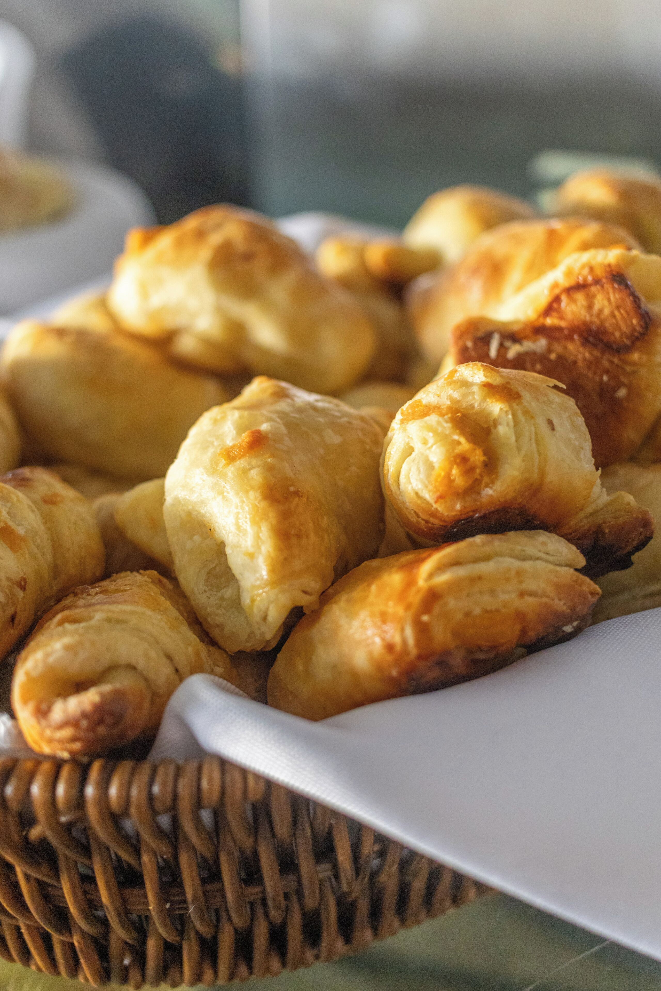A basket of golden-brown pastries, possibly croissants, on a white plate.