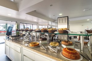 A buffet counter with various baked goods and desserts.
