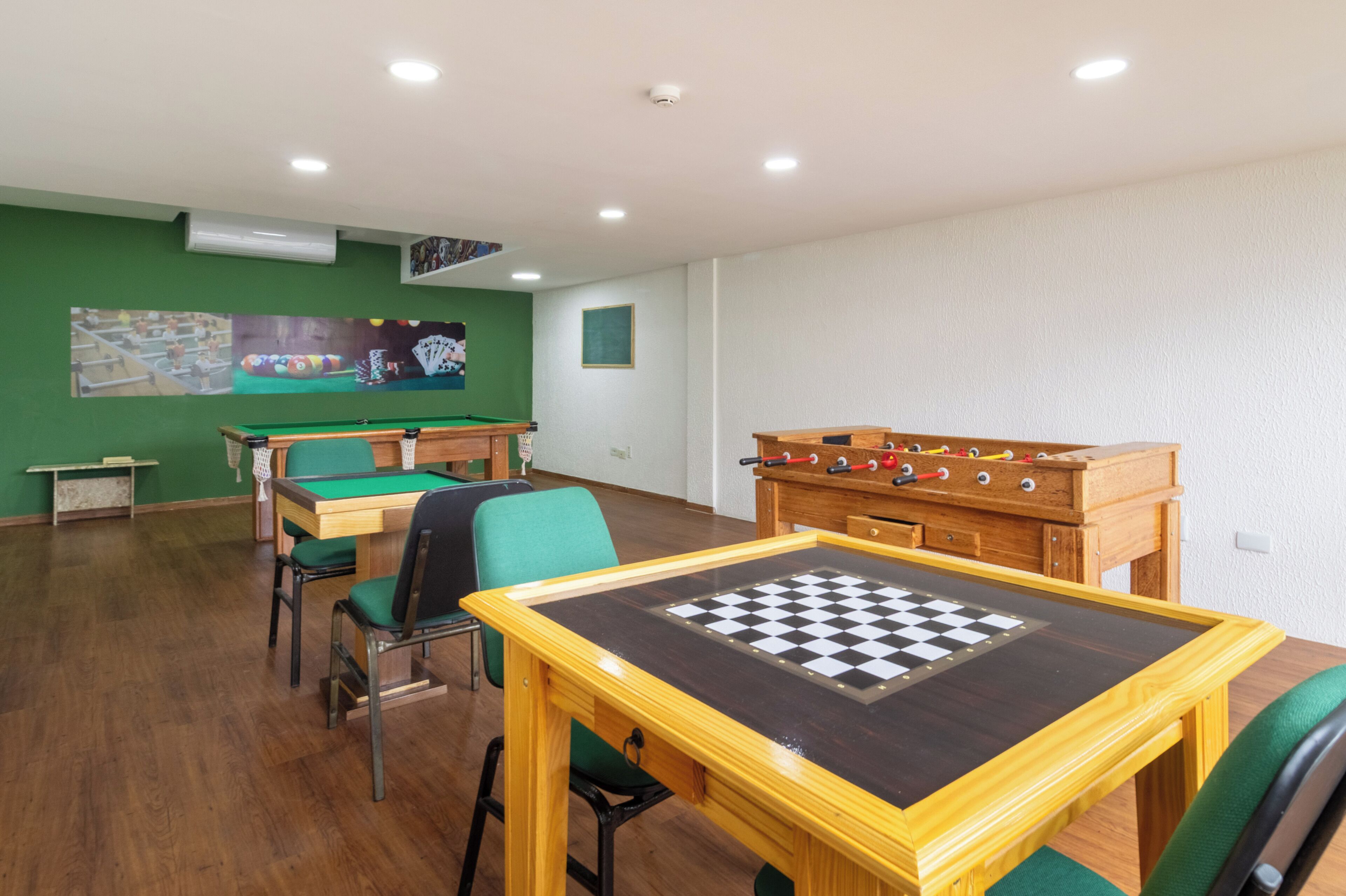 Een kamer met een pooltafel, een tafelvoetbaltafel en een biljarttafel.