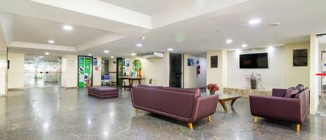 A spacious lobby with a high ceiling, a reception desk, and seating areas.