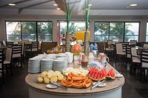 A buffet setup with various fruits, beverages, and plates.