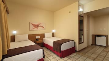 Habitación de hotel con dos camas, un escritorio pequeño, un espejo y una obra de arte en la pared.