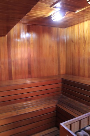 A wooden sauna with benches and a sloped ceiling.