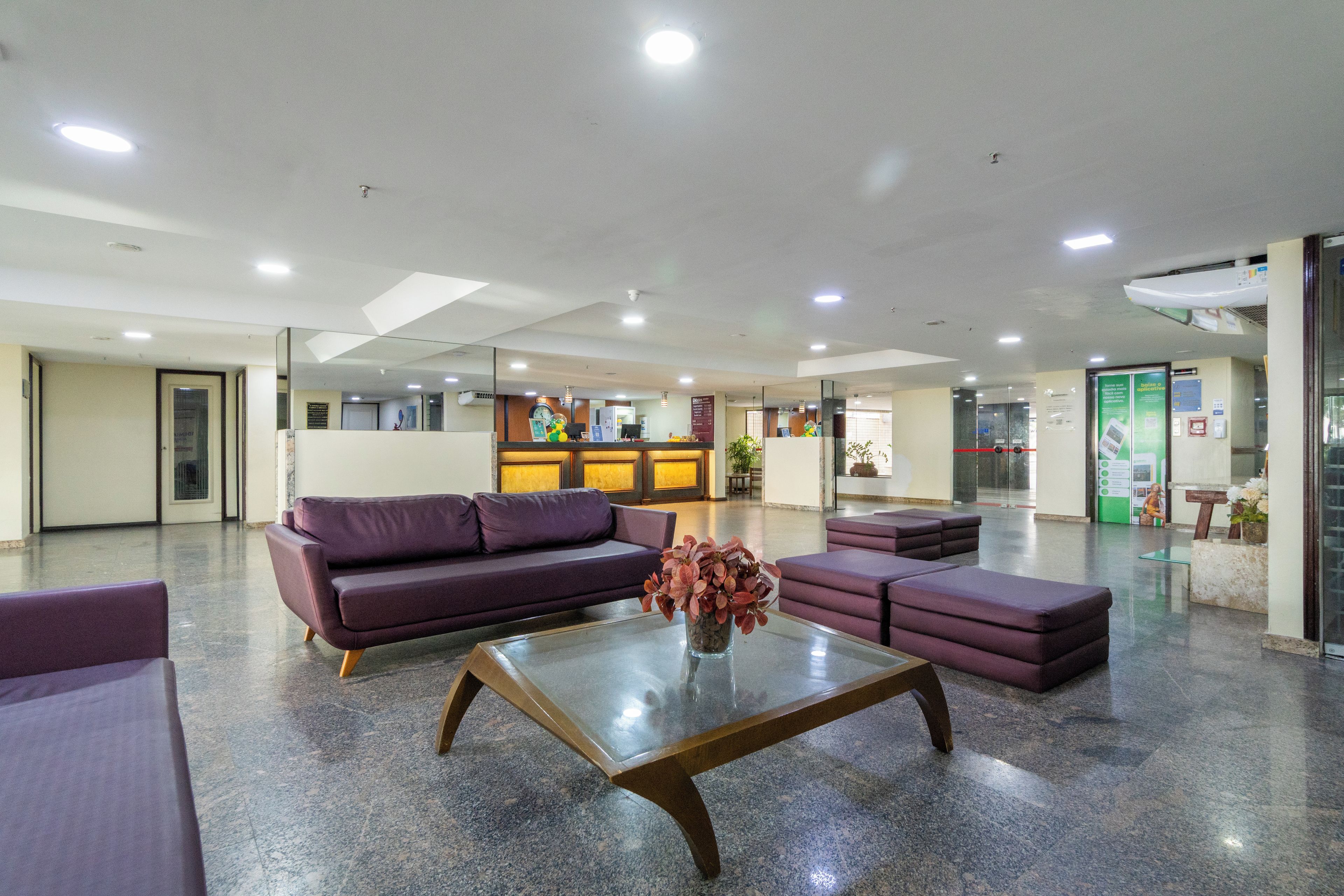 Un vestíbulo con mostrador de recepción, sofás, una mesa de centro y un jarrón decorativo.