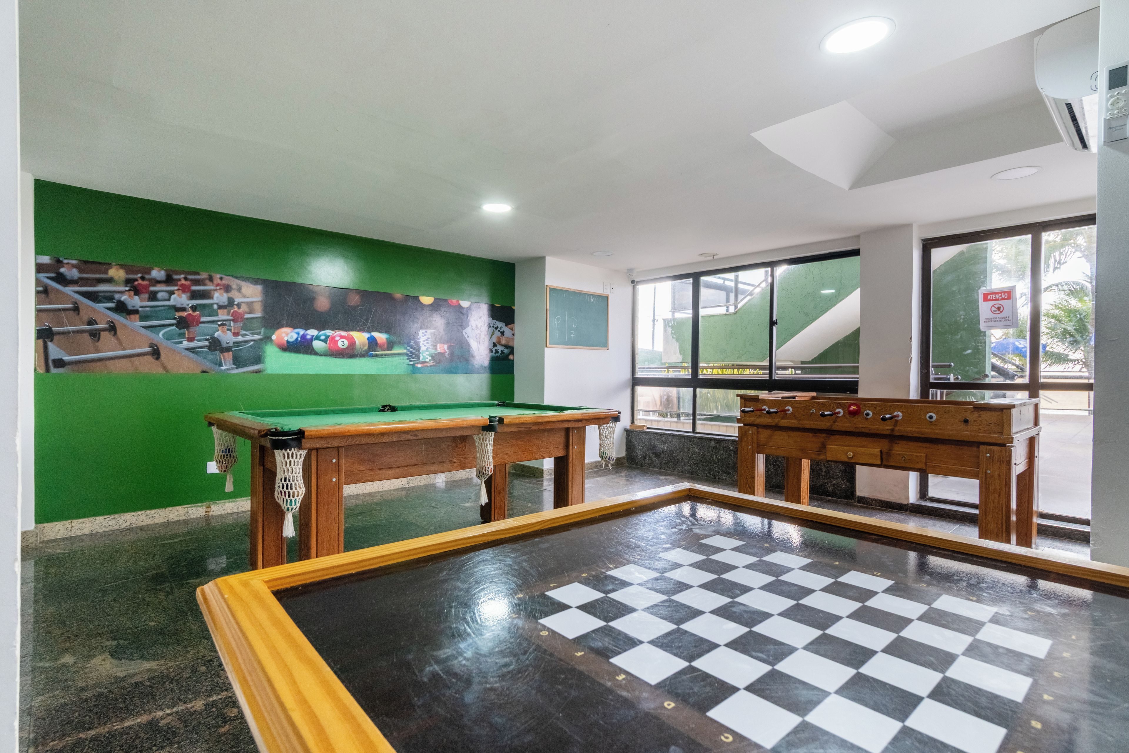 A billiards room with a pool table, two smaller pool tables, and a mural of a billiards scene.