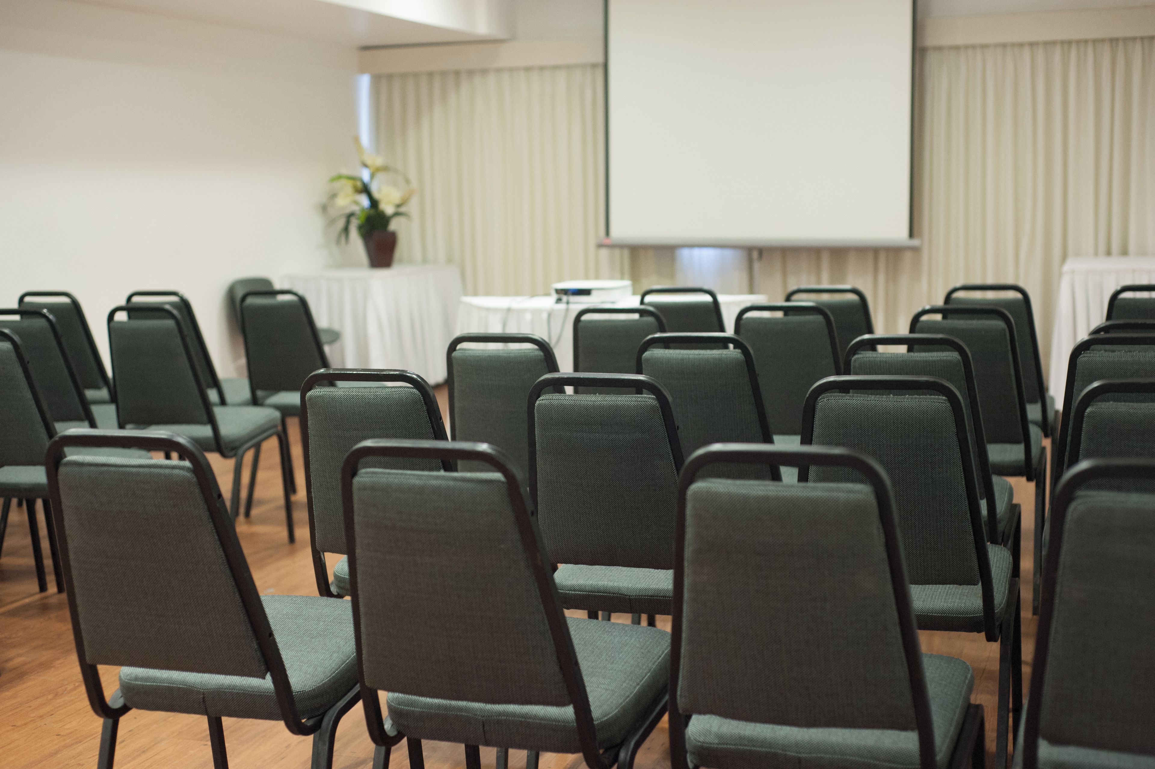 A conference room with rows of chairs facing a projection screen.