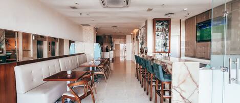 Un restaurante moderno con una barra larga, mesas y una zona de bar.