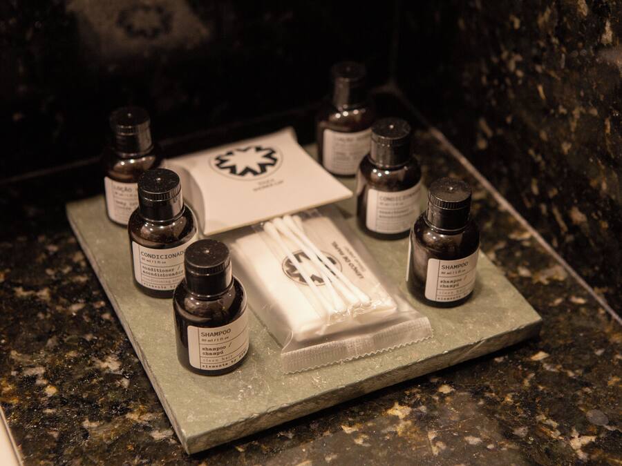 A bathroom counter with various toiletries including bottles of shampoo, conditioner, and a bar of soap.
