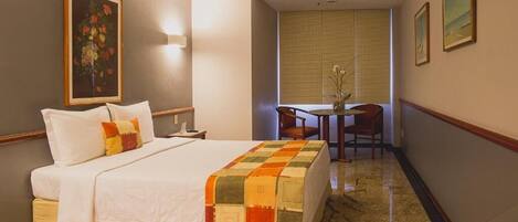 Una habitación de hotel con cama, escritorio y silla.