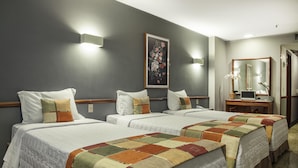 A hotel room with two beds, each with a quilted bedspread and pillows. There is a painting on the wall and a mirror above a wooden dresser. - Hotel Atlantico Star (Rio de Janeiro)
