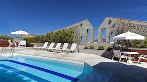 A swimming pool with lounge chairs and umbrellas, surrounded by stone walls and greenery. - Hotel Atlantico Star (Rio de Janeiro)