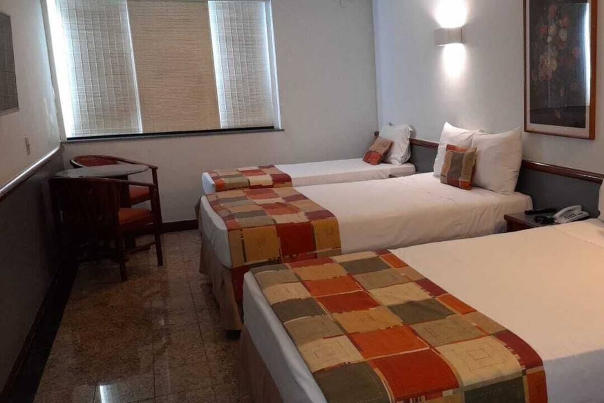A hotel room with two beds, a desk, and a chair.